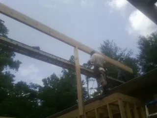 Carpenter setting a ridge beam over a new addition frame — Ice Dam Removal by Roofing Brothers in Nada