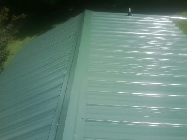 New green metal panels meeting at the ridge of a roof — Flat Roof Repair work by our crew in Nada