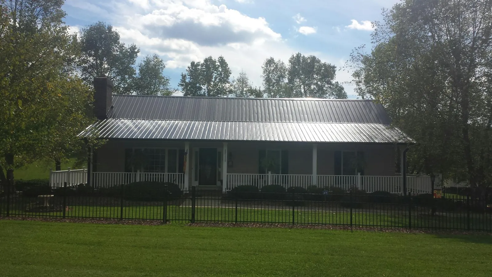 Gray metal roof on a brick ranch with a full width front porch — Gutter Guard Installation work by our crew in Nada