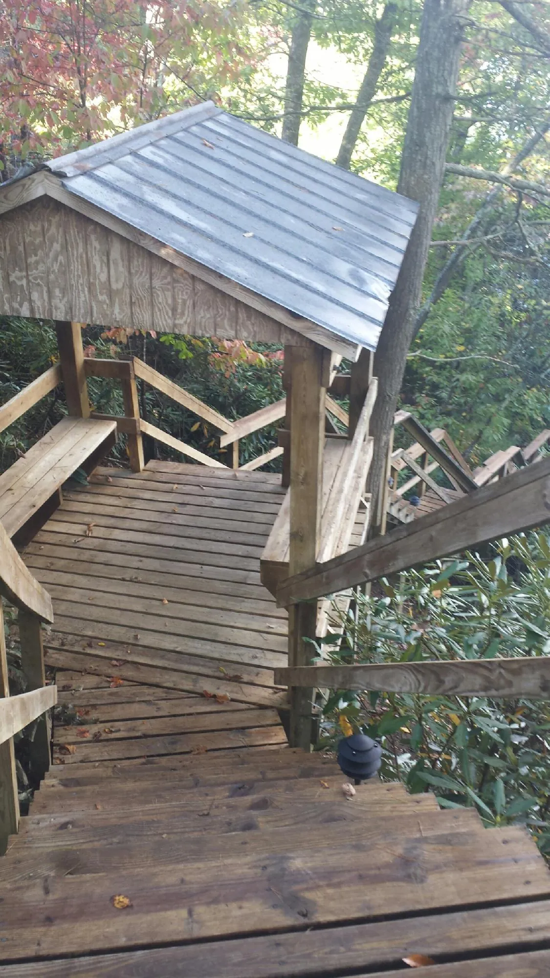 Metal roofed shelter over wooden steps on a wooded walkway — Skylight Repair & Installation work by our crew in Nada
